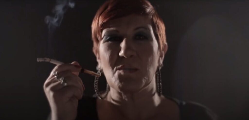 Η κυρία που καπνίζει το τσιγάρο της με προκλητική αδιαφορία για τα τραγικά συμβάντα που διαδραματίζονται παράλληλα στην μικρή ιστορία του βίντεο.